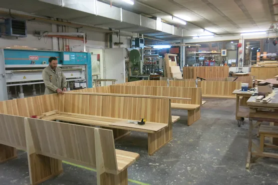 Tischler bei der Montage von Holzsitzbänken in einer Werkstatt