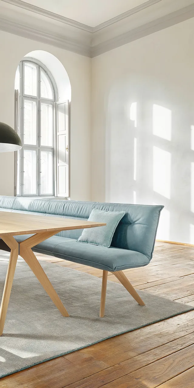 Helles Esszimmer mit Holztisch, blauen Polsterstühlen und großem Bogenfenster