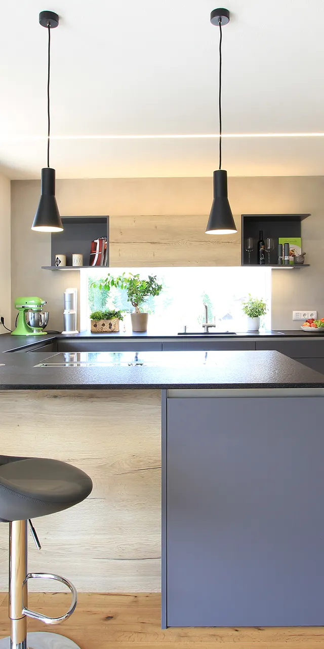 Moderne Einbauküche mit Holzfronten, Kochinsel, Hängelampen und großen Fenstern