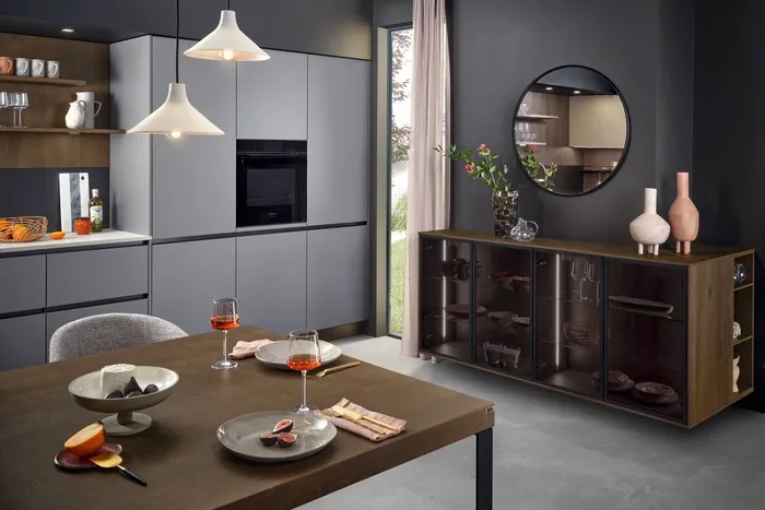 Moderne Küche mit grauen Schränken, Esstisch, Hängelampen und dekorativem Sideboard