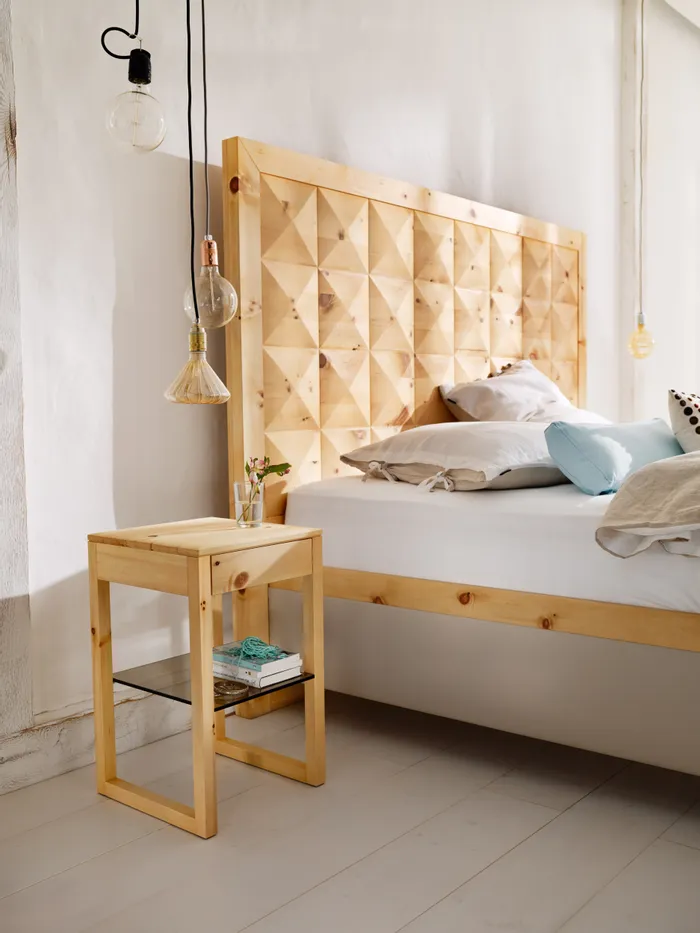 Modernes Schlafzimmer mit Bett und Nachttisch aus hellem Holz neben Hängeleuchten