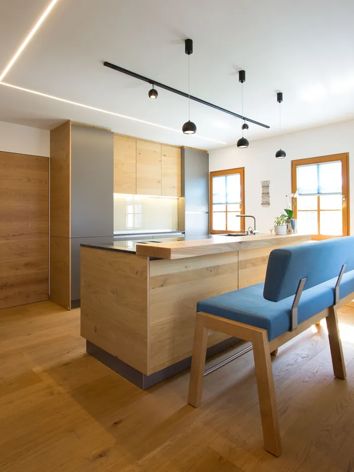 Moderne Küche mit Holzfronten, Kücheninsel, blauer Bank und Hängelampen