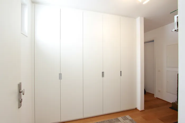 Moderner Einbauschrank mit weißen Türen in einem Flur mit Parkettboden