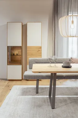 Modernes Esszimmer mit Holztisch, Polsterbank, Vitrine und dekorativer Hängelampe