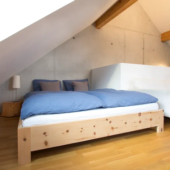Modernes Schlafzimmer im Dachgeschoss mit Holzboden, Doppelbett und blauer Bettwäsche