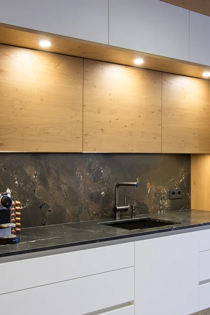 Weiße Küche mit Holzoberschränken und dunkler Steinplatte