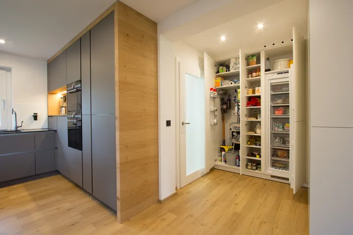 Moderne Küche mit geöffneter Vorratskammer, Regalen und Einbaugeräten auf Holzfußboden