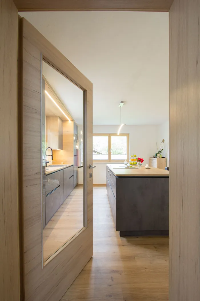 Moderne Küche mit Holzfußboden, Kochinsel und großen Fenstern mit Tageslicht