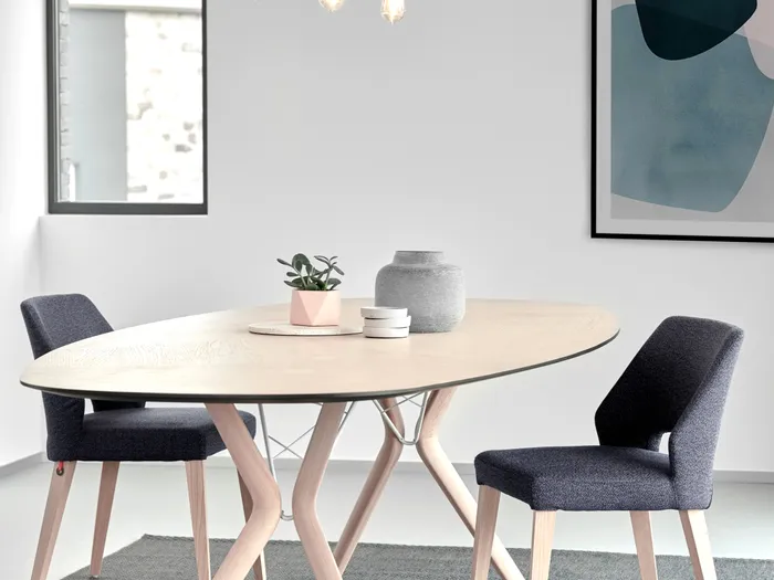 Moderner Esstisch mit hellen Holzbeinen, zwei Stühlen und minimalistischer Dekoration im skandinavischen Stil