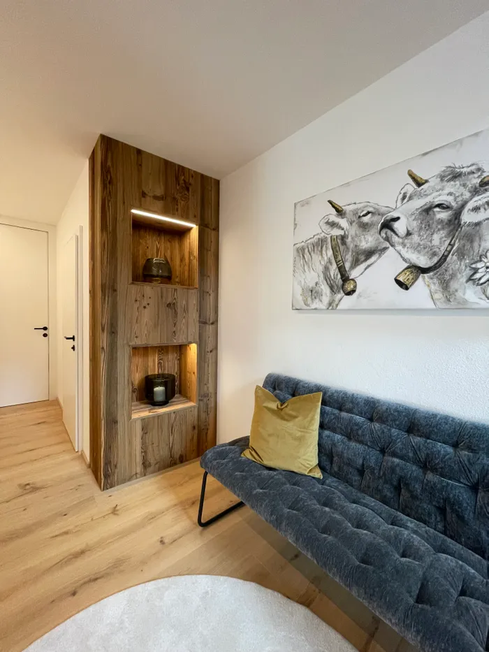 Modernes Wohnzimmer mit grauem Samtsofa, gelbem Kissen und Wandbild von zwei Kühen