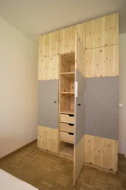 Moderner Einbauschrank aus Holz mit offenen Türen und sichtbaren Schubladen im Schlafzimmer
