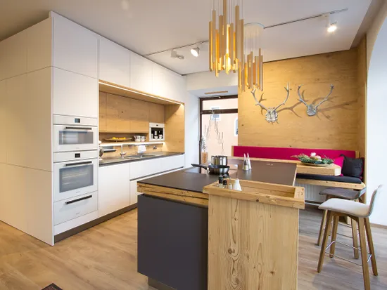 Moderne Einbauküche mit Holzverkleidung, Kochinsel und gemütlicher Sitzecke mit Hirschgeweih-Dekor