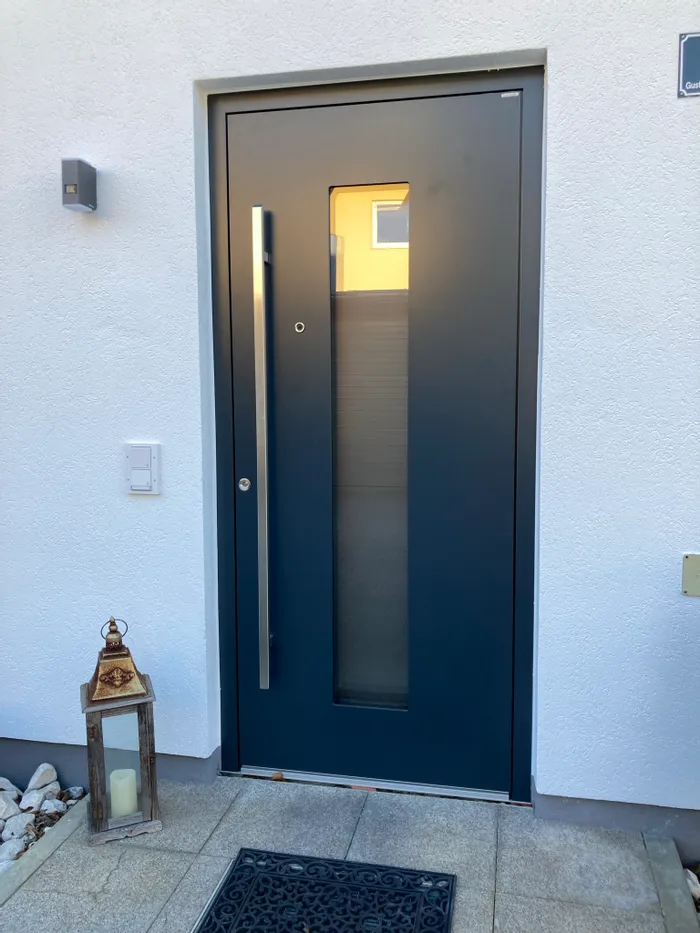 Moderne dunkelblaue Haustür mit Glaseinsatz und Laterne auf Steinfliesen