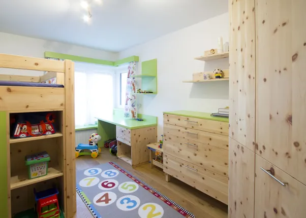 Helles Kinderzimmer mit Holzmöbeln, Etagenbett, Spielzeugregal und buntem Zahlen-Teppich