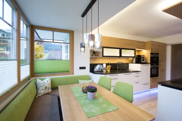 Moderne Wohnküche mit grüner Sitzecke, Holzdetails und stilvoller Hängelampe