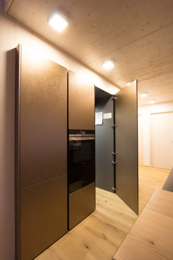 Moderne Einbauküche mit geöffnetem Schranktür und integriertem Backofen im Holzdesign