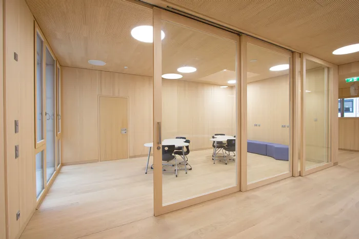 Moderner Besprechungsraum mit Holzwänden, Glastrennwänden und runden Tischen mit Stühlen