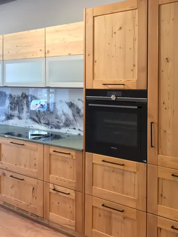 Moderne Einbauküche aus hellem Holz mit schwarzem Wasserhahn und Bergpanorama als Rückwand