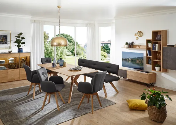 Modernes Esszimmer mit Holztisch, schwarzen Polsterstühlen und goldener Hängelampe in heller Wohnung