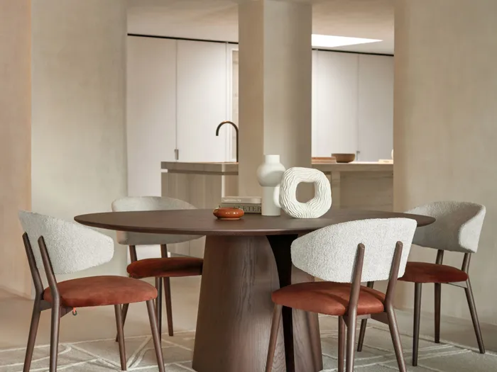 Modernes Esszimmer mit rundem Holztisch, vier gepolsterten Stühlen und dekorativen Keramikvasen