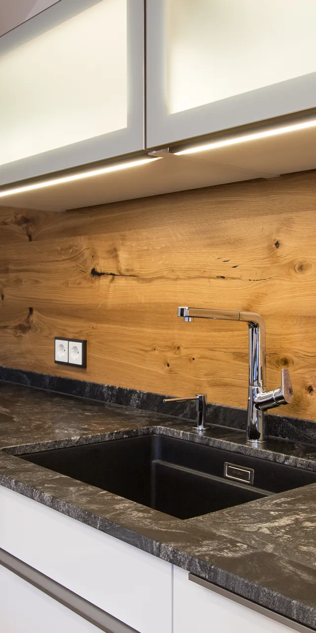 Moderne Küche mit schwarzer Stein-Arbeitsplatte, Holzrückwand und integriertem Spülbecken