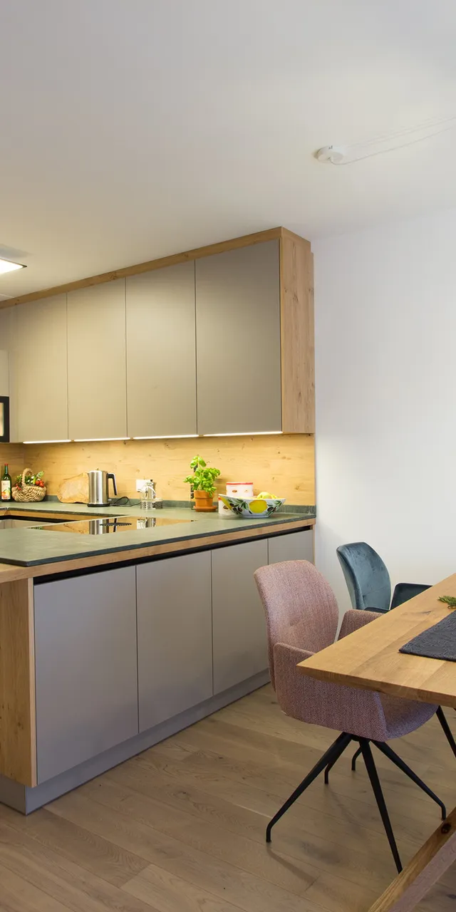 Moderne Einbauküche mit Holzdetails, Kücheninsel und Essbereich mit stilvollen Stühlen