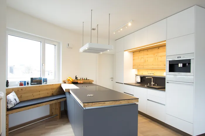 Moderne Wohnküche mit Kochinsel, Holzdetails und integrierter Eckbank am Fenster