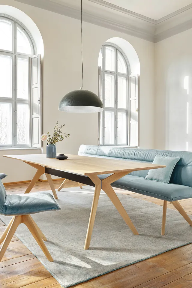 Helles Esszimmer mit Holztisch, blauen Polsterstühlen und großem Bogenfenster