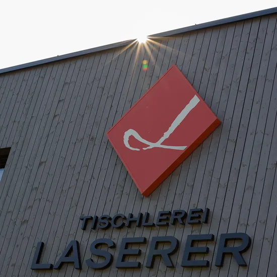 Firmenschild Tischlerei Laserer an Holzfassade bei Sonnenschein