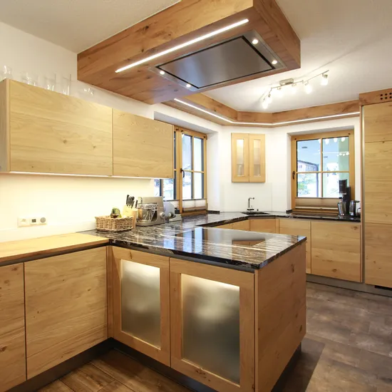 Moderne grifflose Holzküche mit schwarzer Steinplatte