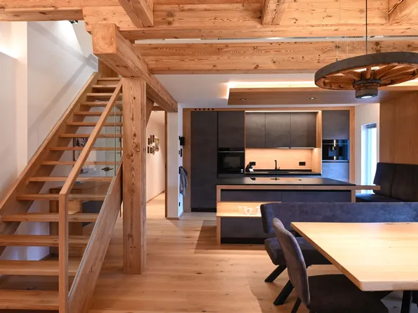 Moderne Küche und Essbereich mit Holzdecke, Treppe und dunklen Möbeln im Landhausstil