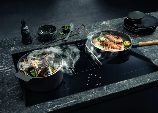 Zwei Töpfe mit Meeresfrüchten auf einem modernen Induktionskochfeld mit integriertem Dunstabzug