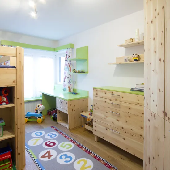 Helles Kinderzimmer mit Holzmöbeln, Etagenbett, Spielzeugregal und buntem Zahlen-Teppich