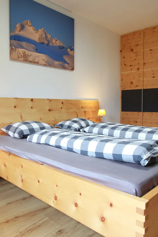Modernes Schlafzimmer mit Massivholzbett, karierten Bettdecken und eingebautem Holzschrank