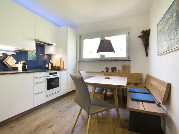 Moderne Küche mit Essbereich, Holzbank und blauen Akzenten auf hellem Holzboden