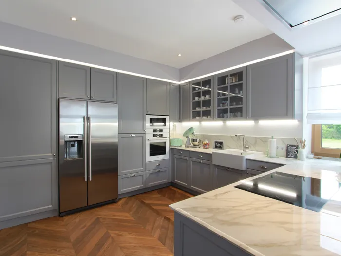 Moderne Küche mit grauen Schränken, Marmorarbeitsplatte und Edelstahlgeräten