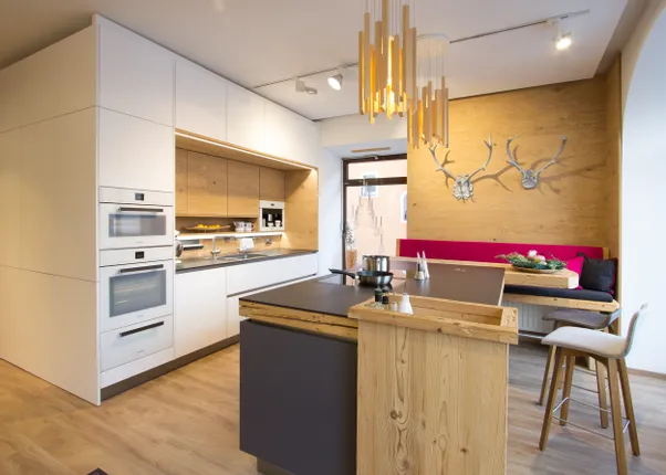 Moderne Einbauküche mit Holzverkleidung, Kochinsel und gemütlicher Sitzecke mit Hirschgeweih-Deko