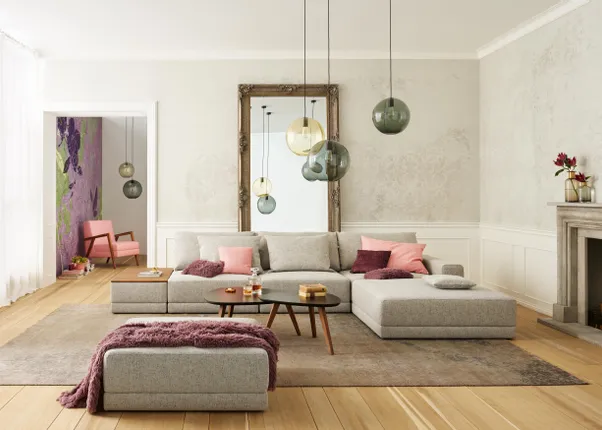 Modernes Wohnzimmer mit grauem Sofa, bunten Kissen, Hängelampen und großem Spiegel