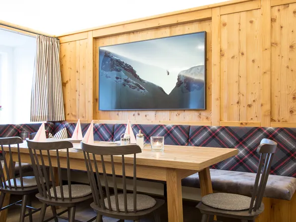 Gemütlicher Essbereich mit Holzmöbeln, kariertem Polster und Bergbild an der Wand