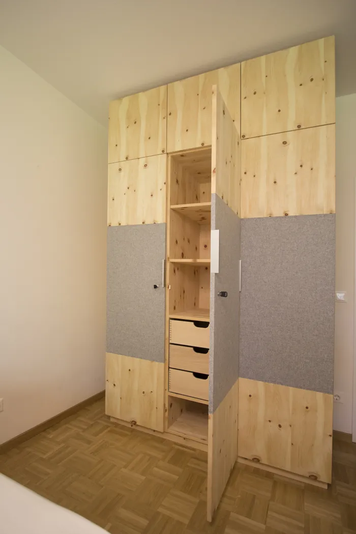 Moderner Einbauschrank aus Holz mit offenen Türen und sichtbaren Schubladen im Schlafzimmer