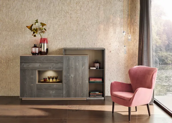 Wohnzimmer mit rosa Sessel, grauer Holzkommode und dekorativen Vasen vor Fenster mit Seeblick