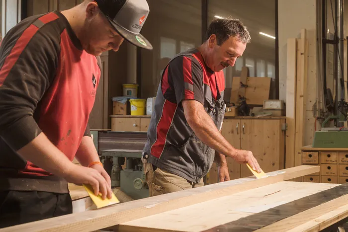 Zwei Schreiner schleifen Holz in einer Werkstatt mit Hand-Schleifklötzen