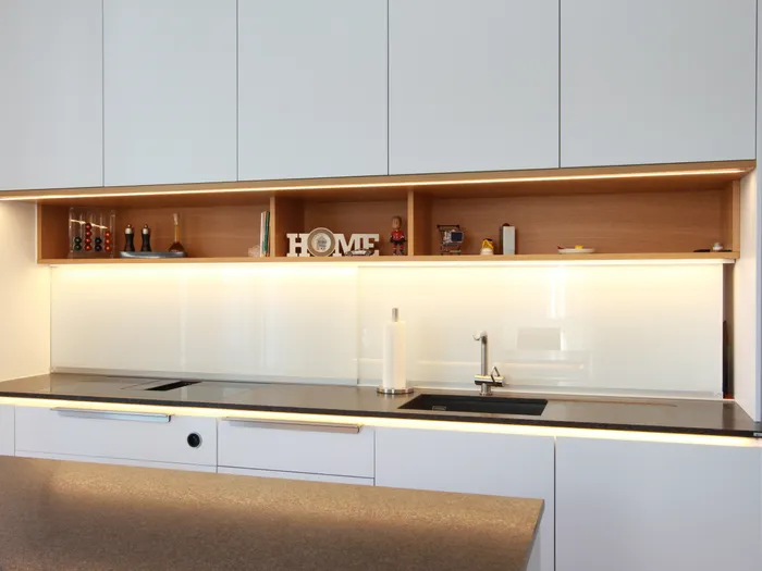 Moderne weiße Küche mit Induktionskochfeld, Spüle und offenen Regalen mit Beleuchtung