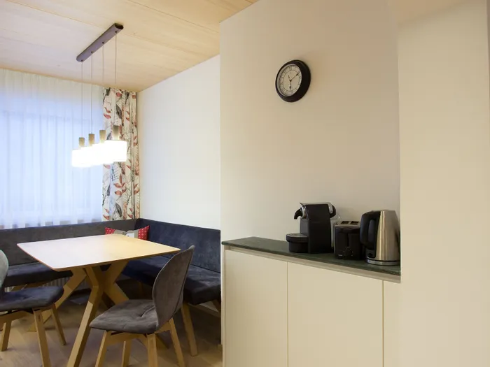 Moderne Frühstücksecke mit Holztisch, Polsterbank und Kaffeemaschine auf Sideboard