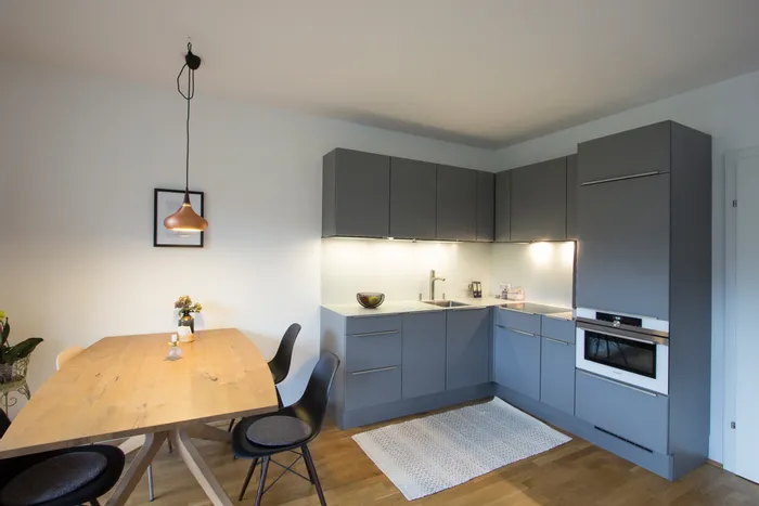 Moderne graue Einbauküche mit Holz-Esstisch und hängender Designerlampe