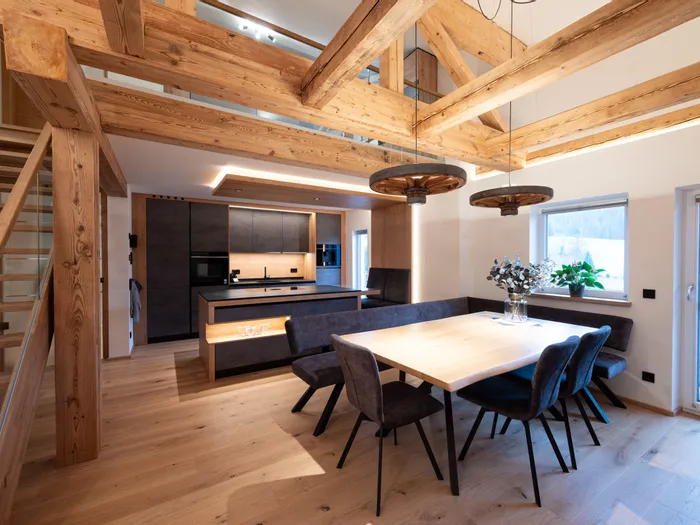 Moderne Küche mit Essbereich aus Holz, schwarzen Möbeln und sichtbaren Holzbalken