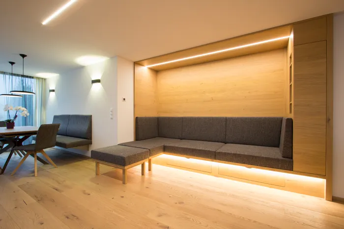 Modernes Wohnzimmer mit eingebautem Holzsofa und indirekter Beleuchtung