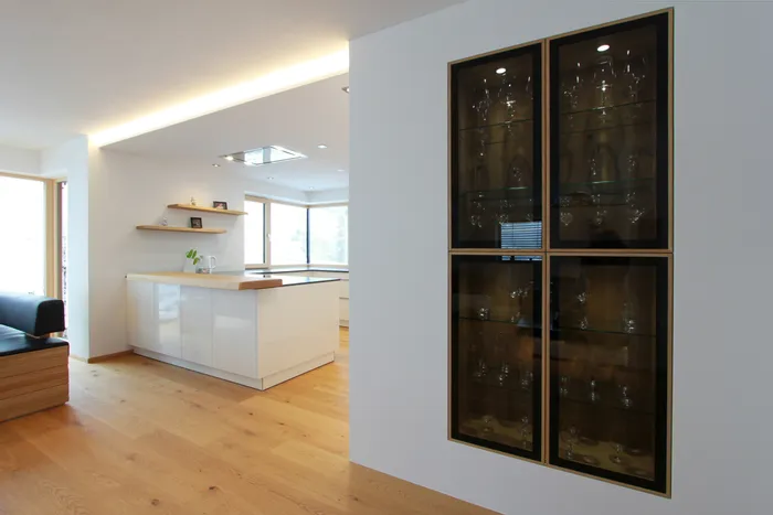 Moderne offene Küche mit weißen Hochglanzfronten und wandintegriertem Gläserschrank