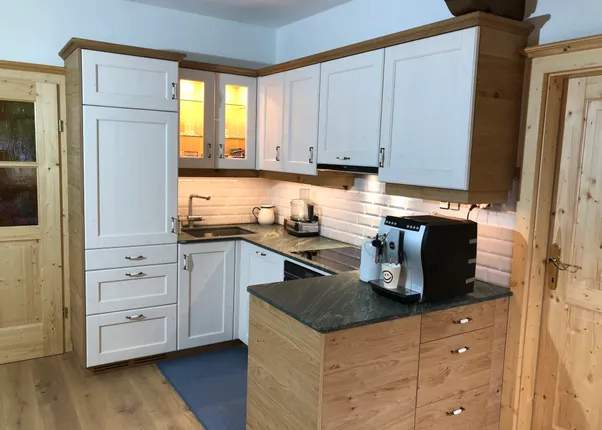 Moderne Küche mit Holzfronten, weißen Oberschränken und Kaffeemaschine auf der Arbeitsplatte