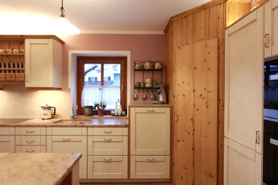 Gemütliche Landhausküche mit Holzschränken, Espressomaschine und Blick aus dem Fenster